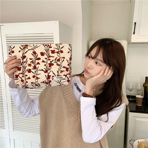 Trousse à maquillage en velours côtelé à fleurs tenue par un mannequin en cuisine