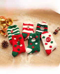 Close-up of cozy coral fleece Christmas socks with festive patterns on snowy wood surface