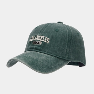 Close-up of vintage embroidery on washed cotton dark green baseball cap with white text