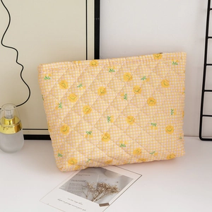 Detail of quilted yellow checkered makeup bag with floral patterns and smiley faces