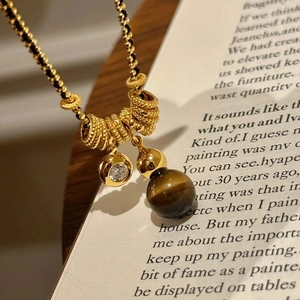 Close-up of gold-plated tiger eye necklace with zircon stones on vintage book