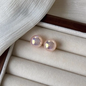 Close-up of pink mermaid pearl stud earrings presented in a luxury off-white jewelry box