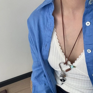 Détail du pendentif mousqueton cœur argenté avec breloques sur cordon marron