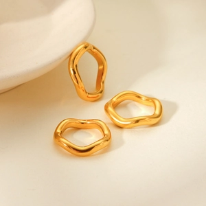 Detail shot of three wave-shaped gold plated stainless steel rings with organic texture