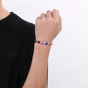 Dettaglio di perline colorate e bracciale in corda intrecciata nera con chiusura magnetica al polso