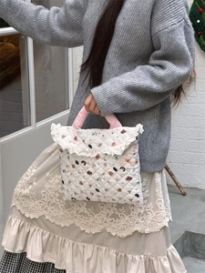 Detail of quilted cartoon dog laptop bag with white lace trim and soft pink handles