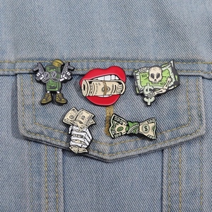 Street style enamel pins with money and skull motifs shown on a denim jacket pocket