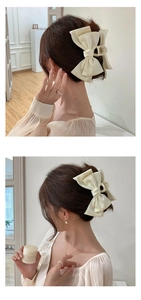 Detail of cream oversized satin bow hair claw clip styled in a chic updo for women