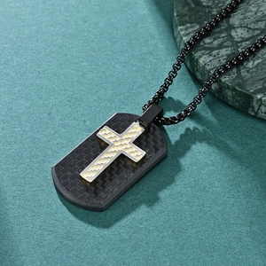 Men's shield-shaped carbon fiber cross pendant necklace in black and gold on marble