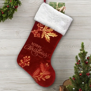 Detail of red velvet Christmas stocking with gold Merry Christmas embroidery on wood table