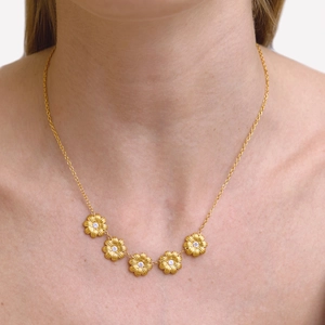 Détail du collier marguerite en acier inoxydable or 18 carats avec zircon blanc sur la clavicule