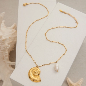 Vue macro du pendentif nautile en or 18 carats avec perle baroque sur chaîne ajustable