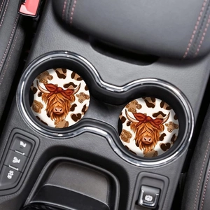 Close-up of dual round highland cow car coasters with leopard print in a vehicle cup holder