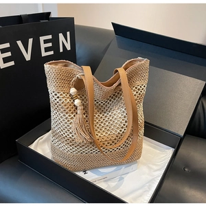 Detail of woven straw tote bag with brown PU leather straps and tassel on gift box