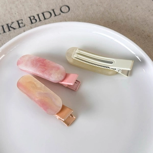 Three-piece hair clip set with marble patterns and translucent finish on a ceramic tray