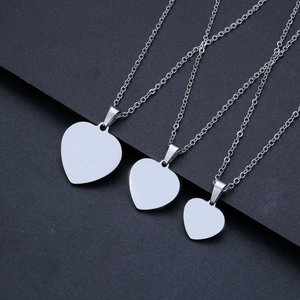 Three polished stainless steel heart pendants in different sizes on dark textured background