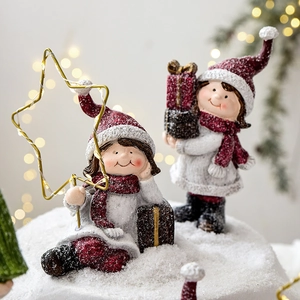Christmas resin figurines of boys in winter clothes on snow background with LED star lights