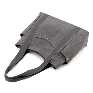 Grey canvas tote bag with front metal snap button pocket and dual handles on white background