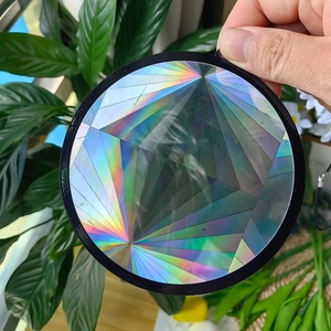Handheld circular suncatcher with rainbow holographic prism effects and geometric patterns