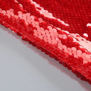 Macro view of overlapping bright red sequins on a backless long-sleeved dress