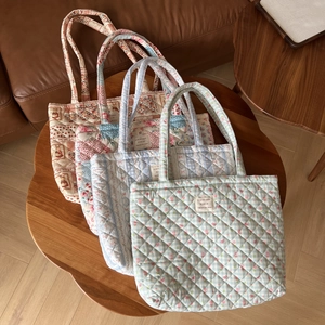 Macro shot showing four floral quilted tote bags in various pastel colors and patterns