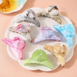 Eight multi-color marble texture shell-shaped hair claws on a white decorative tray