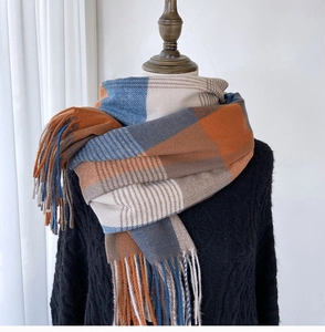 Detail shot of the orange and blue plaid scarf fringe and soft knit texture
