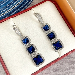 Macro view of long silver drop earrings featuring square blue sapphire cubic zirconia