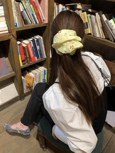 Dettaglio dell'elastico in tessuto giallo con fiori di perline in una biblioteca