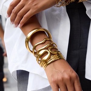 Close-up of layered 18K gold stainless steel bangles with wavy and polished line designs