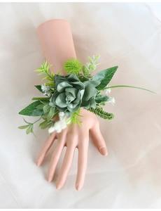 Detail of artificial green succulent wrist corsage with white flowers on model hand