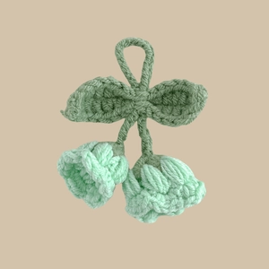 Detail of handmade crochet lily of the valley keychain in mint green and white yarn