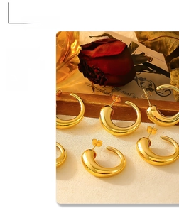 Detailed view of polished 18k gold plated C-shape hoop earrings on a vintage prop backdrop
