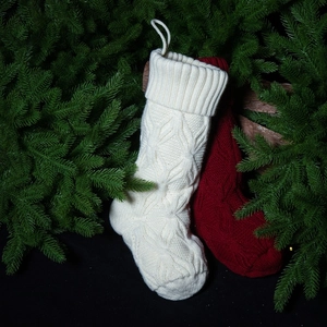 Knitted Christmas stockings in cream and dark red with cable stitch pattern on pine branches