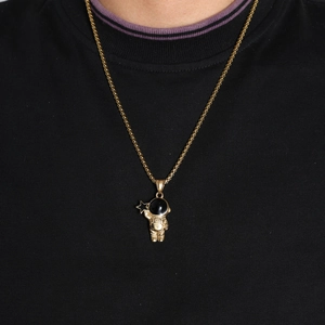 Close-up of golden astronaut pendant with star detail on a black crew neck shirt