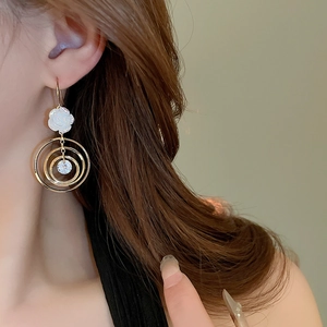 Détail de boucle d'oreille rose avec anneaux dorés et zircon brillant sur modèle