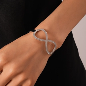 Dettaglio del bracciale simbolo infinito con cristalli su cordoncino nero indossato da modella