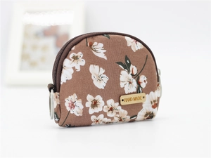 Detail of floral fabric coin purse showing zipper and handmade label on white background