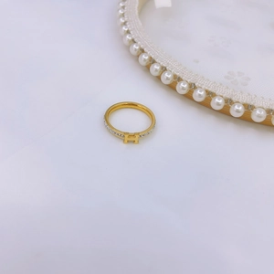 Luxurious gold H-letter ring with sparkling cubic zirconia pavé on a white textured background