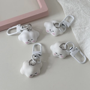 Detail of four cute cloud keychains with smiles and closed eyes on a white desk