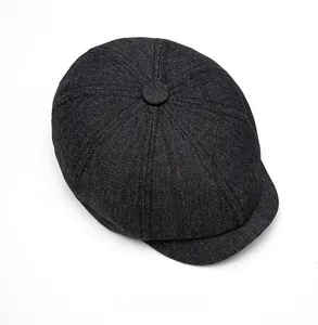 Top view of black denim newsboy cap showing the eight-panel crown and fabric button detail