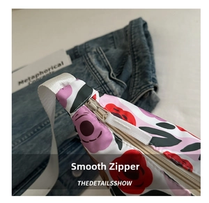 Close-up of a smooth white zipper detail on a floral print shoulder bag with fabric strap