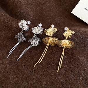 Vue détaillée de boucles d'oreilles à pompons en or et argent avec pétales et zircon