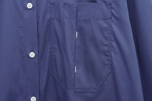 Close-up of pocket stitching and white buttons on a dark blue long-sleeve casual shirt