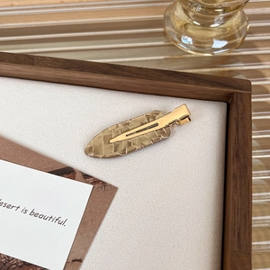 Detail view of the metal duckbill clip back and marble-patterned resin on the hairpin
