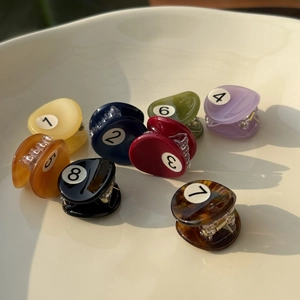 Eight colorful acetate mini hair claws in billiard style shown in a ceramic bowl