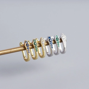 Macro detail of snake-shaped U-shaped earrings with colorful zircons in gold and silver