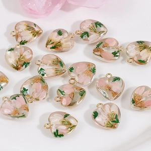 Detail view of heart-shaped resin pendants with pink dried flowers and gold loops