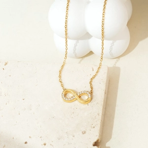 Elegant gold infinity necklace with heart-shaped zircon inlay on minimalist stone base