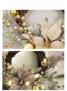 Detail of Christmas wreath with gold baubles, frosted needles, and warm LED lights